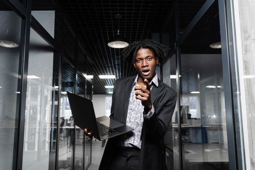 Happy black man pointing his fingers in camera and rejoice finishing his online job on laptop. Working online in coworking space