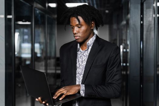 Black man freelancer with laptop in coworking space. Online working on laptop