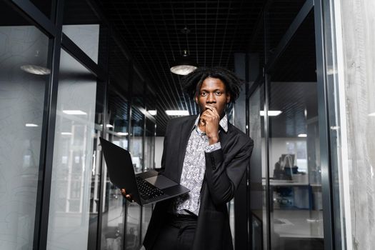 Happy black man clenched fists and rejoice finishing his online job on laptop. Working online in coworking space