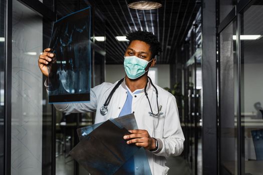 African doctor examines x-rays in a medical clinic. Black student in medical mask is studying and looking at ct scans