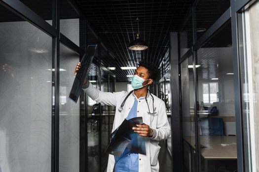 African doctor with x-ray scan in medical clinic. Black medical student in medical mask study in university