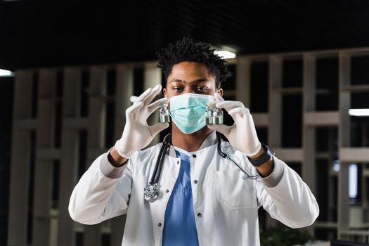 Black doctor with 3 doses of vaccine. Booster vaccination. African doctor in medical mask is holding vaccines in hand