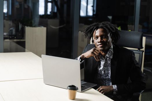 Black business man with laptop is working online in the office. Handsome african manager is doing remote work in coworking space