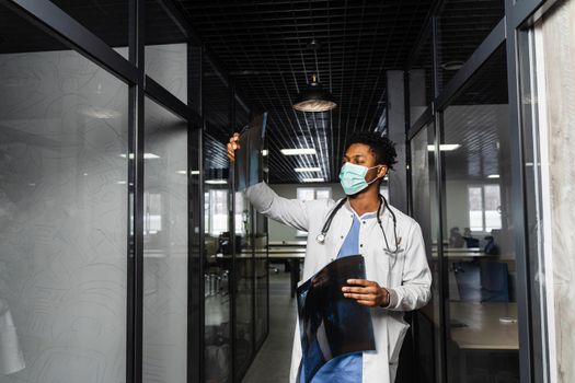 African doctor examines x-rays in a medical clinic. Black student in medical mask is studying and looking at ct scans