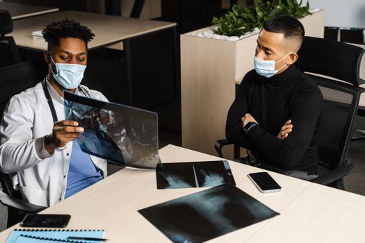 African doctor show x-ray asian patient. Black surgeon analyzing x ray and diagnosis patient in medical clinic