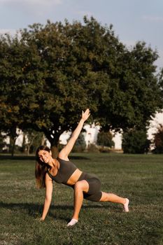 Fit girl does warm-up and stretching exercises in green park. Sports lifestyle