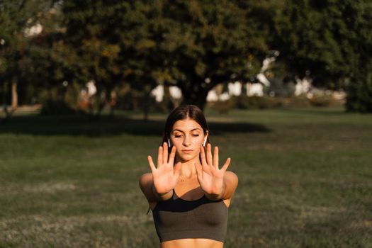 Asian girl does qigong meditation in the green park. Young woman stand in special stance and do special hand movement