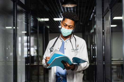 African doctor in mask with books in medical clinic. Black medical student study in university