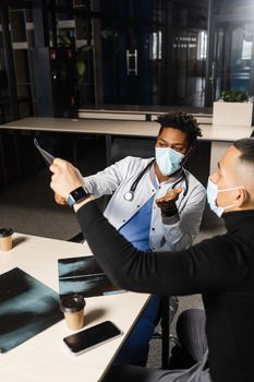 African doctor show x-ray asian patient. Black surgeon analyzing x ray and diagnosis patient in medical clinic