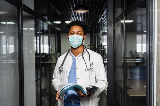 African doctor in mask with books in medical clinic. Black medical student study in university