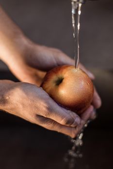 close up. a man washes a red Apple under the tap