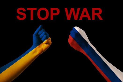 Fist fight flags of Ukraine and russia with text stop war on black background. Putin invasion