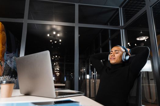 Sleepy and tired asian man working overtime at laptop in office and taking break