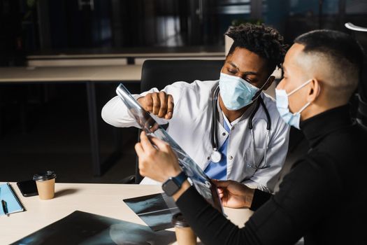 African doctor show x-ray asian patient. Pneumonia and pleurisy. Black surgeon analyzing x ray and diagnosis patient in medical clinic