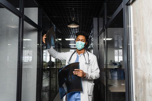 African doctor examines x-rays in a medical clinic. Black student in medical mask is studying and looking at ct scans