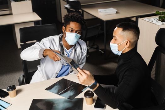 African doctor show x-ray asian patient. Pneumonia and pleurisy. Black surgeon analyzing x ray and diagnosis patient in medical clinic