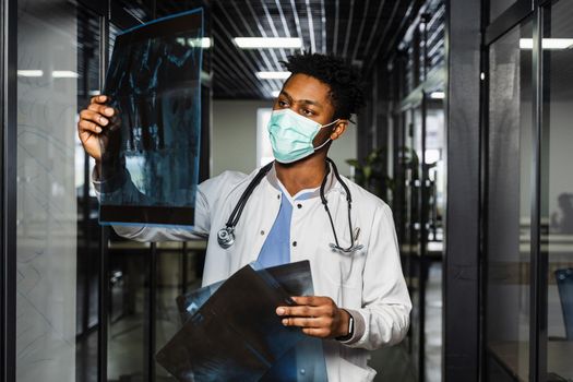 African doctor examines x-rays in a medical clinic. Black student in medical mask is studying and looking at ct scans