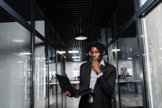 Confident black business man with laptop working online with his colleagues. Handsome african manager in the office