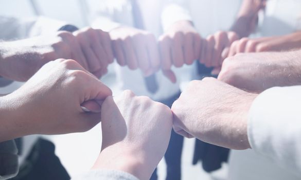 close up. business team forming a circle, out of their fists.the concept of unity and support