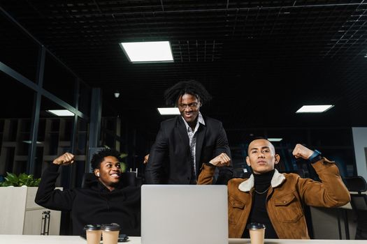 Teambuilding black Africans and Asians. Positive mixed race colleagues smile, rejoice in teamwork success on a joint project