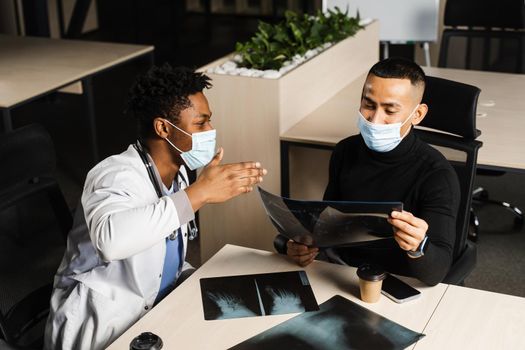 African doctor show x-ray asian patient. Black surgeon analyzing x ray and diagnosis patient in medical clinic