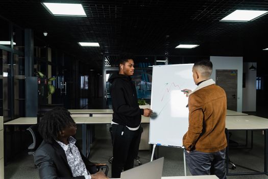 Cryptocurrencies and bitcoin graph discussion by multiethnic investors. Black African and Asian businessmen are discussing the economic financial situation together