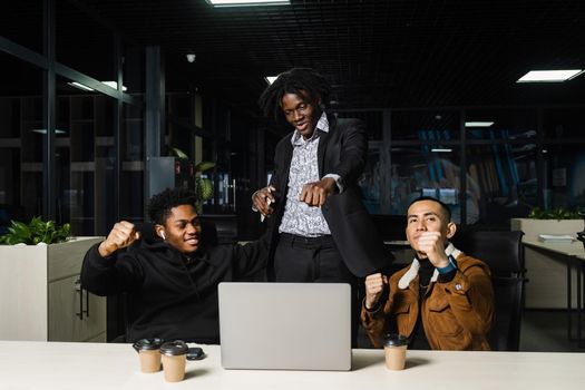 Teambuilding black Africans and Asians. Positive mixed race colleagues smile, rejoice in teamwork success on a joint project