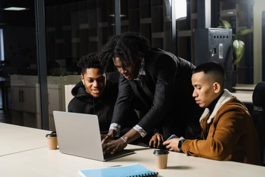 Multiethnic group teamwork of black african and asian employee working on laptop together. Discuss business process in team in office