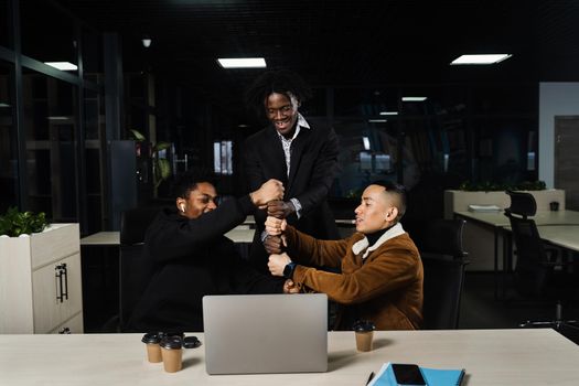 African and Asian colleagues making hand stack of fists. Multiethnical diverse teamwork online with laptop. Community spirit and friendship. Keeping high motivation