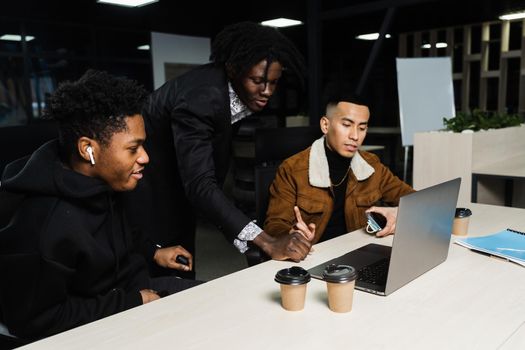 Teamwork of 2 black african and asian with laptop. Colleagues in informal clothes working on business project in the office