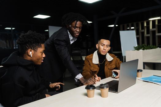 Teamwork of 2 black african and asian with laptop. Colleagues in informal clothes working on business project in the office