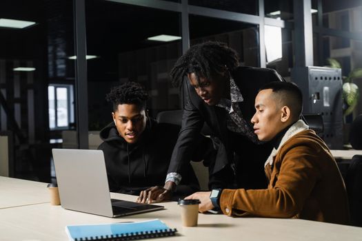 Multiethnic group teamwork of black african and asian employee working on laptop together. Discuss business process in team in office