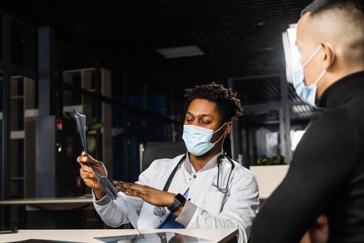 African doctor show x-ray asian patient. Black surgeon analyzing x ray and diagnosis patient in medical clinic