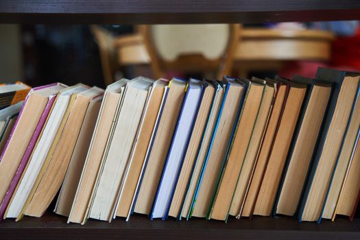 Piles of books on a wooden bookshelf. Home library