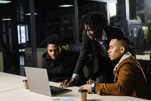 Multiethnic group teamwork of black african and asian employee working on laptop together. Discuss business process in team in office