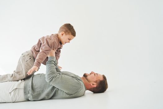 Paternity lifestyle. Father lifting child on white background. Dad and child smile and having fun together