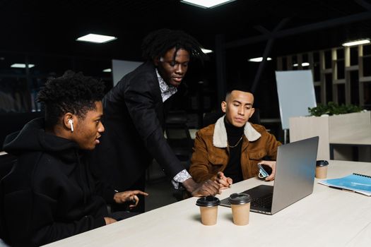 Teamwork of 2 black african and asian with laptop. Colleagues in informal clothes working on business project in the office