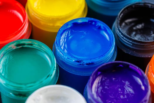 full-frame close-up background of opened small gouache paint jars on black