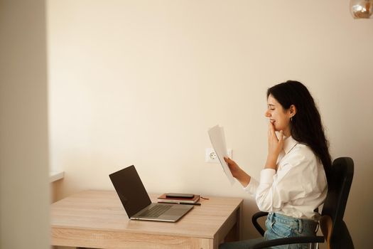 Student girl passed exam and rejoices at high mark. Online education and distance learning. Woman applicant with laptop holds papers with exam results in his hands and rejoices