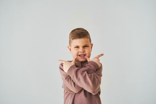 Happy handsome child boy smiling and points his fingers up for choose. Business advertising for children stores and shops