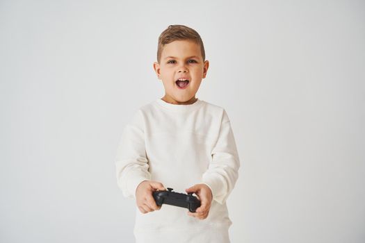 Expressive boy gamer plays computer games with a gamepad. Children's gambling