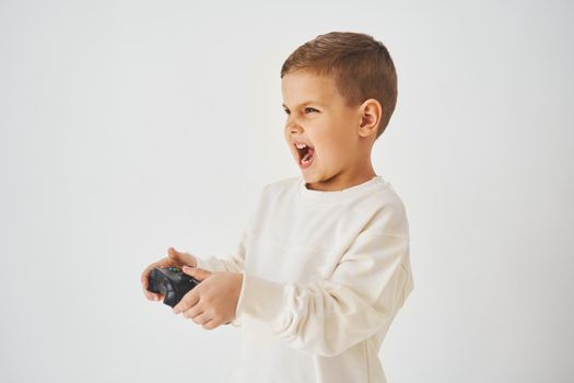 Emotional child with gamepad on white background. Boy is playing games