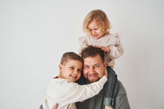 Close-up portrait of father, son and daughter. Happy family hugging and smiling on white background. Paternity. Single father bring up his children