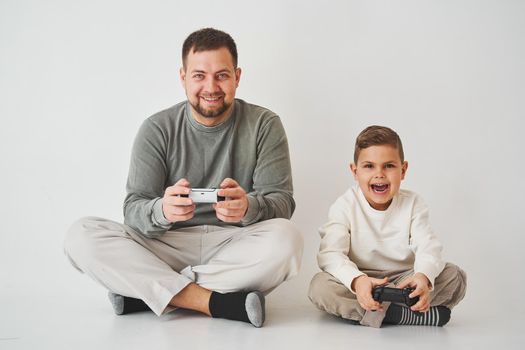 Son and dad play console games with gamepad. Boy and his father spend time togerher and playing computer games