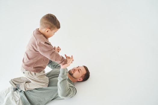 Father and son have fun and fool around together on white background. Child laughs with dad. Fatherhood. Child care