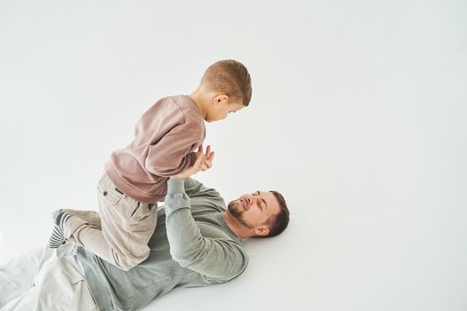 Father and son have fun and fool around together on white background. Child laughs with dad. Fatherhood. Child care