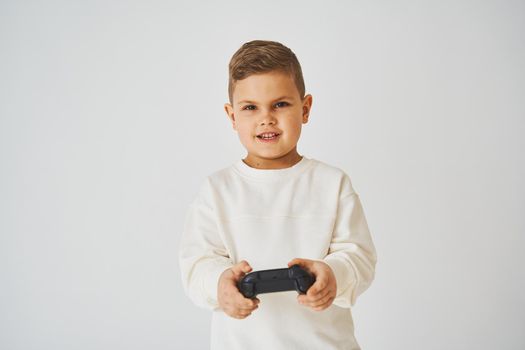 Happy child with gamepad on white background. Boy is playing games