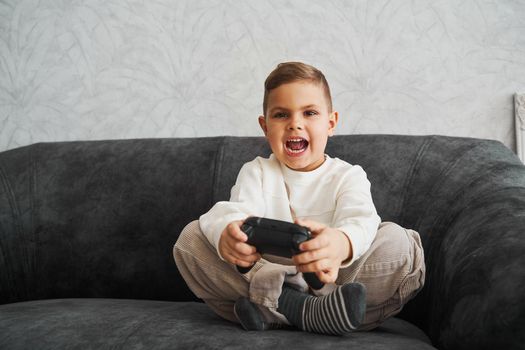 Surprised kid with gamepad playing console games at home. Gambling addiction of child