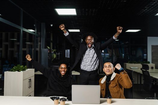 Teambuilding black Africans and Asians. Positive mixed race colleagues smile, rejoice in teamwork success on a joint project