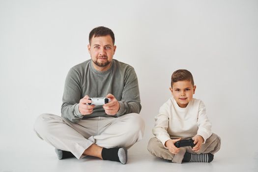 Son and dad play console games with gamepad. Boy and his father spend time togerher and playing computer games